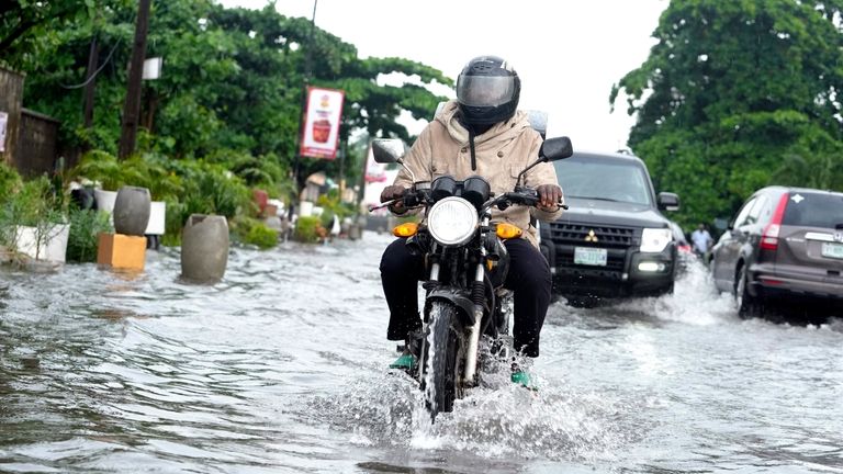 A motorcyclist rides through a flooded street after a heavy...