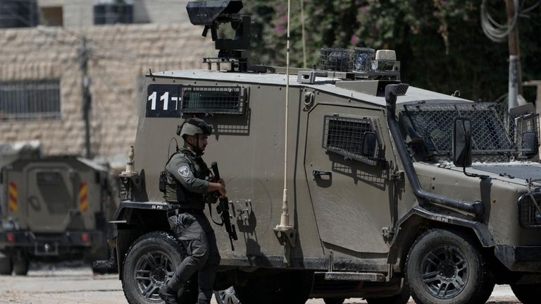 A member of the Israeli forces walks next to an...