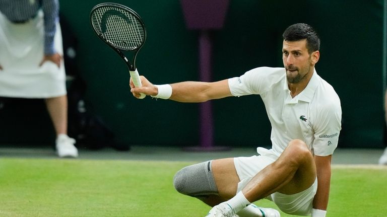 Novak Djokovic of Serbia falls during his fourth round match...