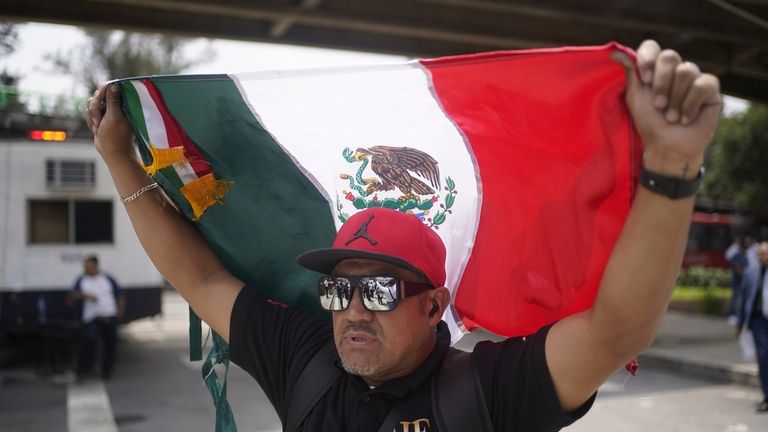 Judicial worker Marcos Arenas holds up a Mexican flag during...