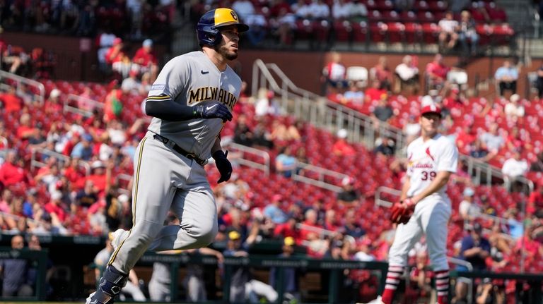 Milwaukee Brewers' Victor Caratini, left, rounds the bases after hitting...