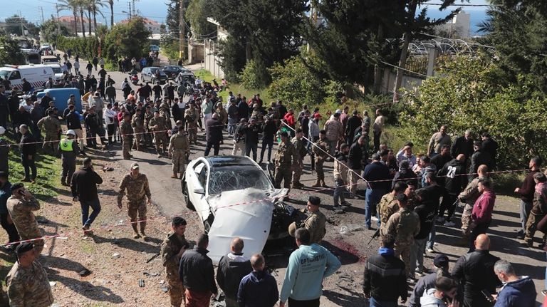 Lebanese army soldiers gather around a damaged car near the...