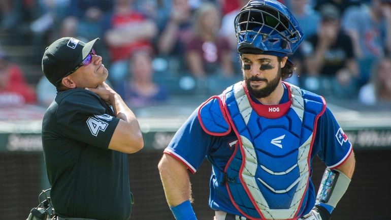 Umpire Roberto Ortiz, left, holds his neck after being hit...