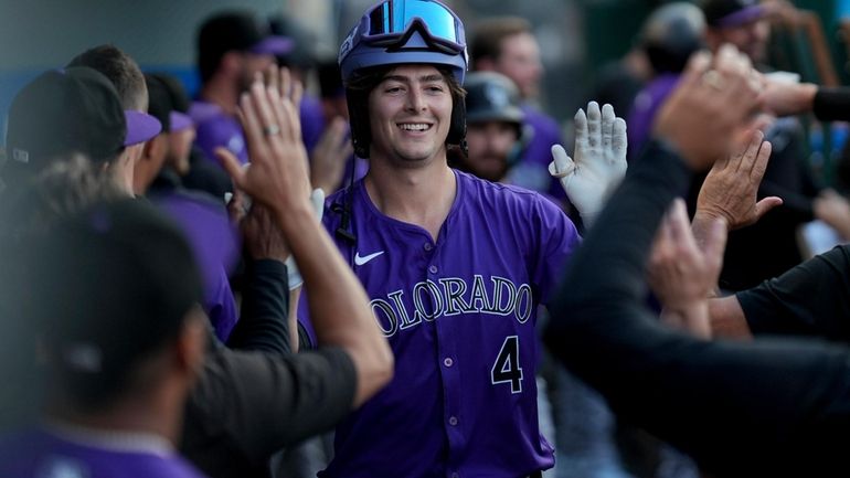 Colorado Rockies' Michael Toglia (4) celebrates in the dugout after...