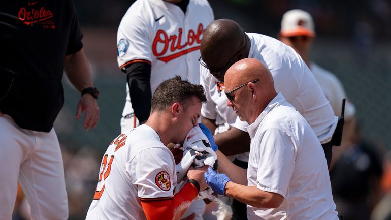 A trainer and coaches attend to Baltimore Orioles' James McCann...