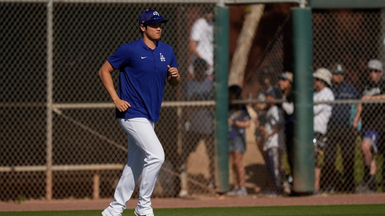 Los Angeles Dodgers' Shohei Ohtani jogs on to a practice...