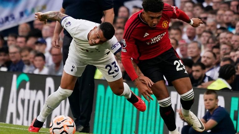 Manchester United's Jadon Sancho, right, and Tottenham's Pedro Porro challenge...