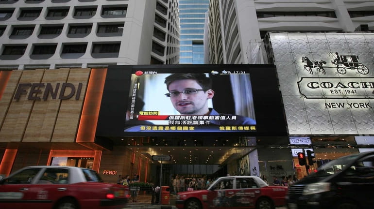 A screen shows a news report on Edward Snowden, a...