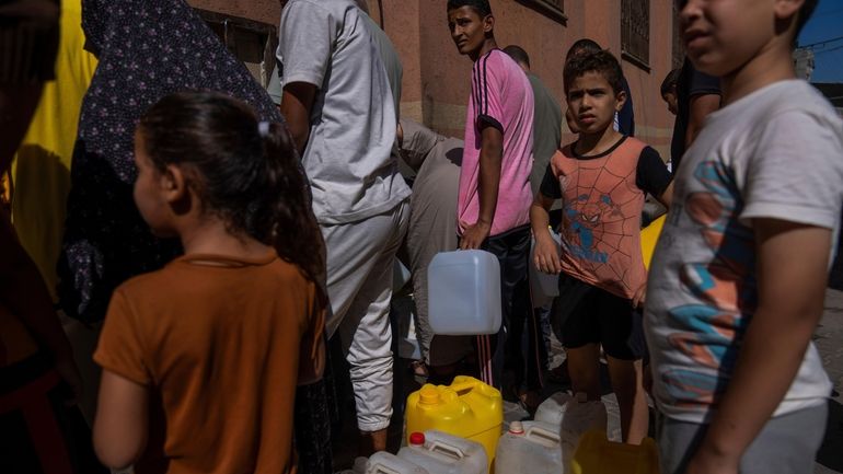 Palestinians collect water from a water tap, amid drinking water...