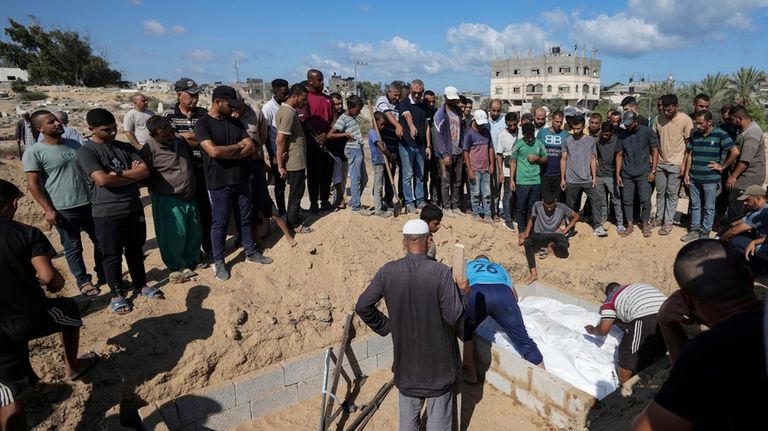 Palestinian grave digger Sa'di Baraka, center, oversees a burial in...