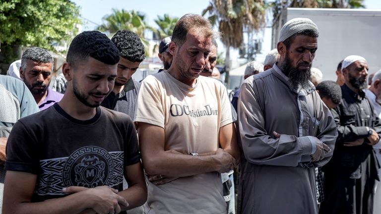 Mohammad Abu Al-Qumsan, Center, prays next to the bodies of...