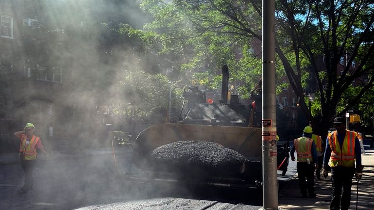 A road crew repaves a road in the Forest Hills...