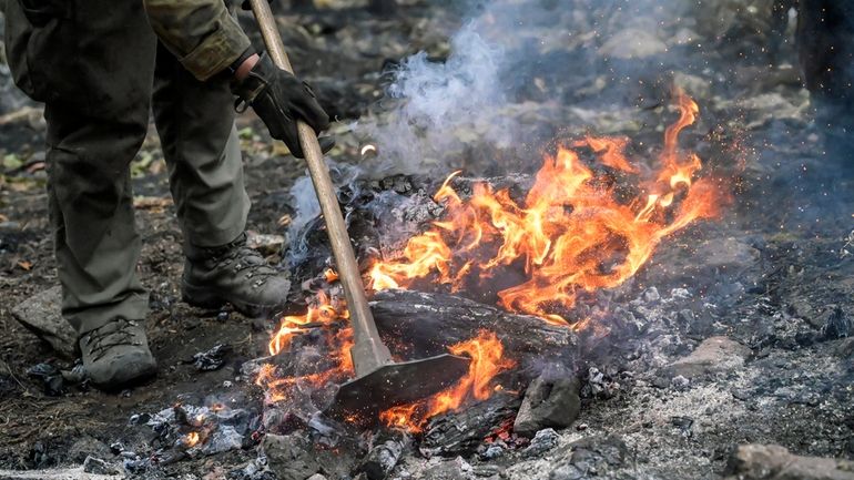 A hotshot works to burnout a bone pile while battling...