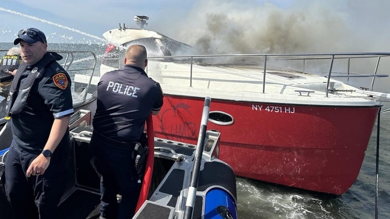 Suffolk County Police Marine Bureau officers extinguish a fire that...
