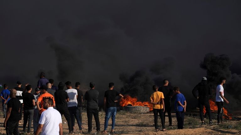 Palestinian protesters gather while burning tires during clashes with Israeli...