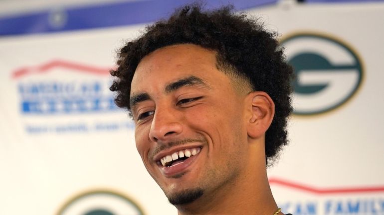 Green Bay Packers quarterback Jordan Love smiles as he listens...