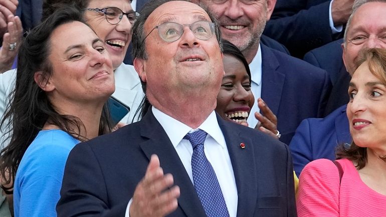 Former French President Francois Hollande looks up as he poses...