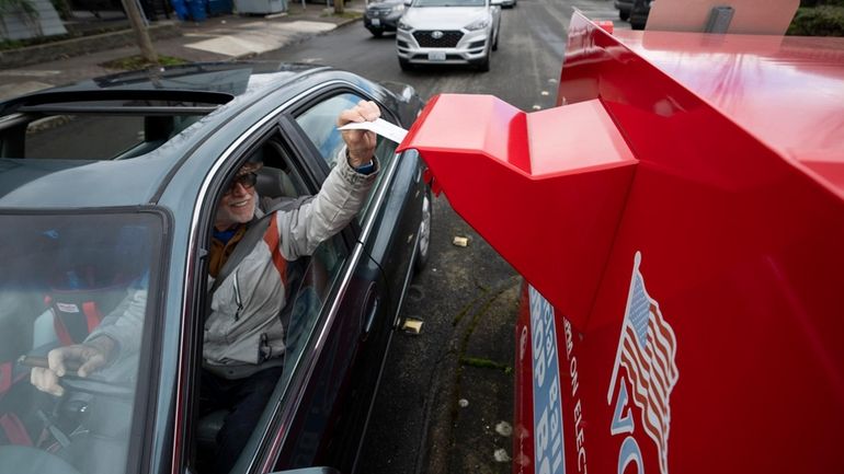 A voter drops off a vote-by-mail ballot on March 12,...