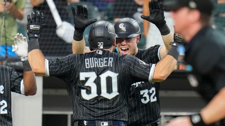 Chicago White Sox's Eloy Jimenez, left, celebrates with Luis Robert Jr.,  right, after they score on a two-run home run by Jimenez during the seventh  inning in the first baseball game of