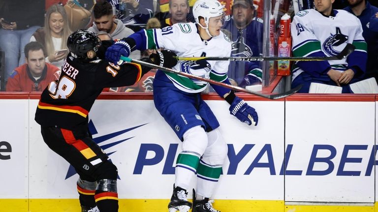 Vancouver Canucks defenseman Nikita Zadorov, right, swats away a check...