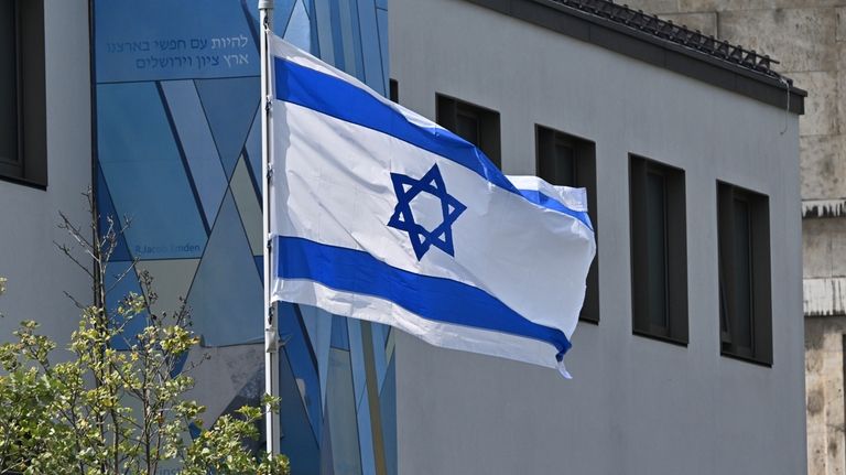 The flag of Israel flies in front of the Israeli...