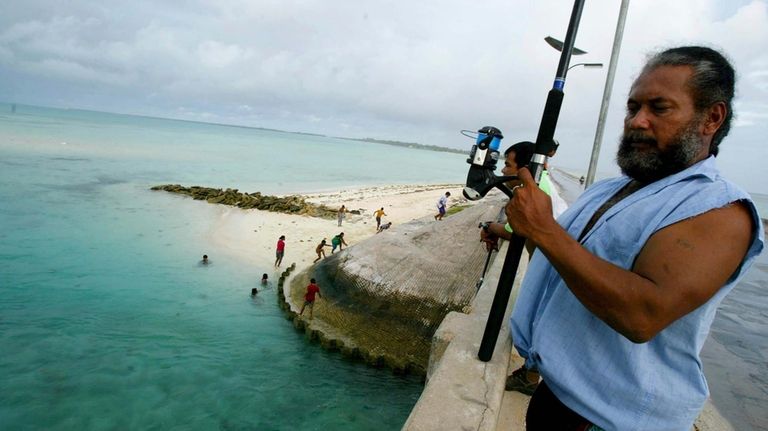 A man fishes on a bridge on Tarawa atoll, Kiribati,...