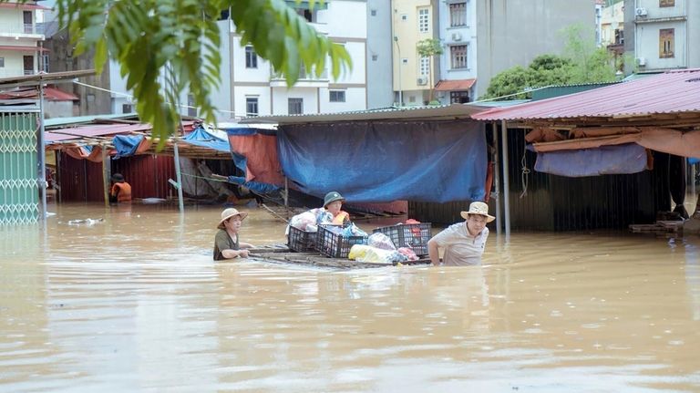 People carry belongings in flood triggered by Typhoon Yagi in...