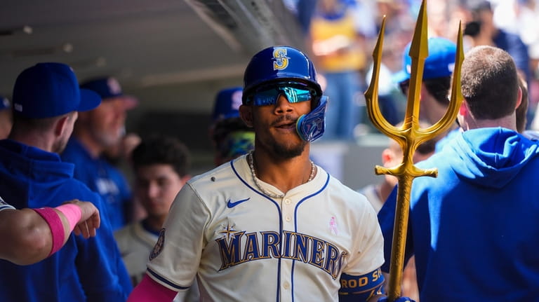 Seattle Mariners' Julio Rodríguez holds a trident in the dugout...