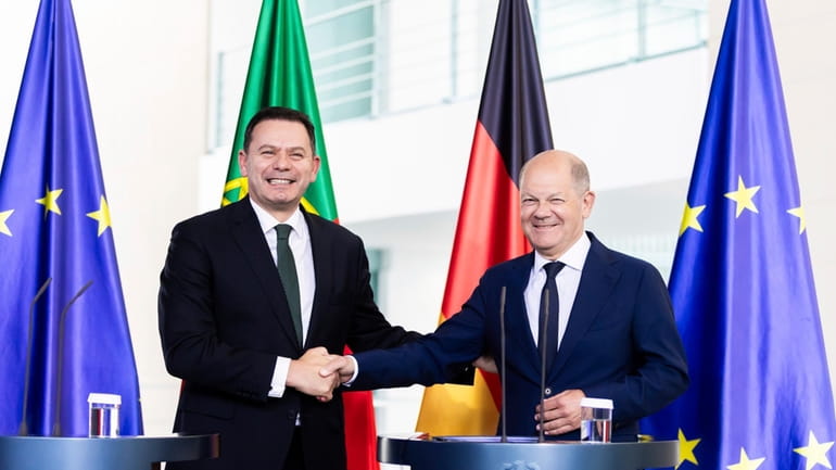 German Chancellor Olaf Scholz, right, shakes hands with Prime Minister...