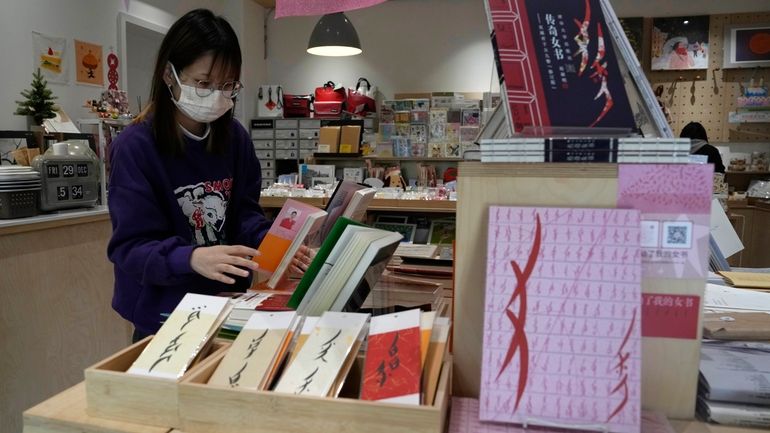 A worker arranges books at a bookstore specializing in nüshu,...