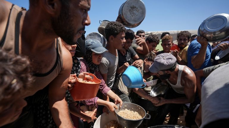 Displaced Palestinians gather for food distribution in Deir al Balah,...