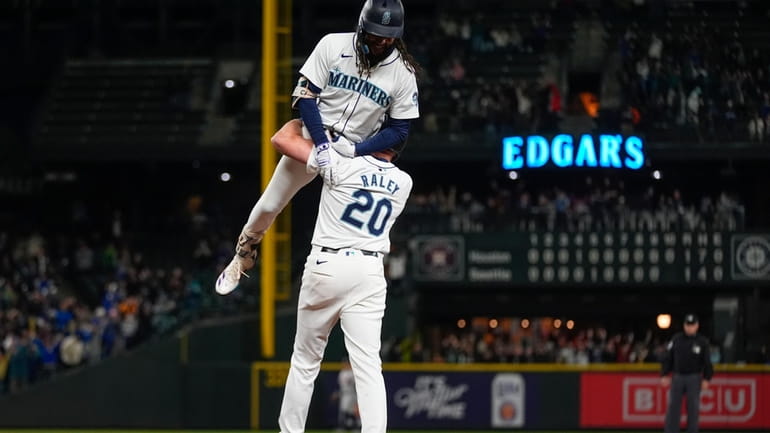 Seattle Mariners' J.P. Crawford is lifted by Luke Raley (20)...