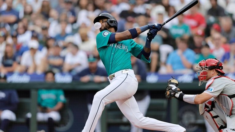 Seattle Mariners' Victor Robles blows a gum bubble as he...