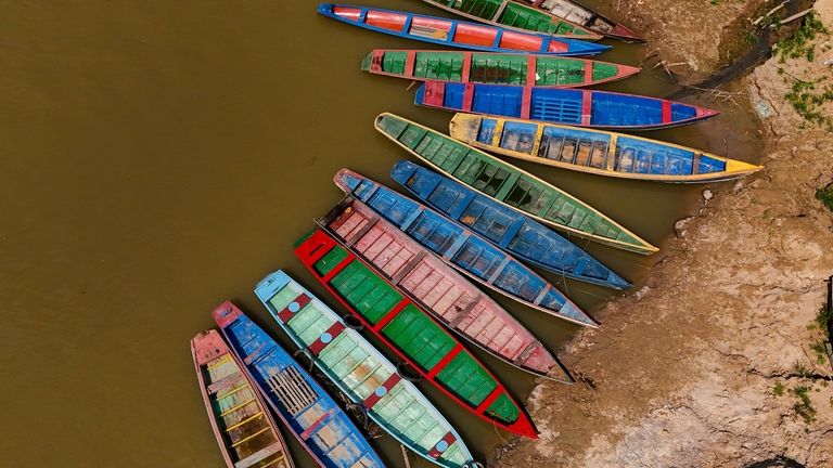 Boats sit on the bank of the Acre River, the...