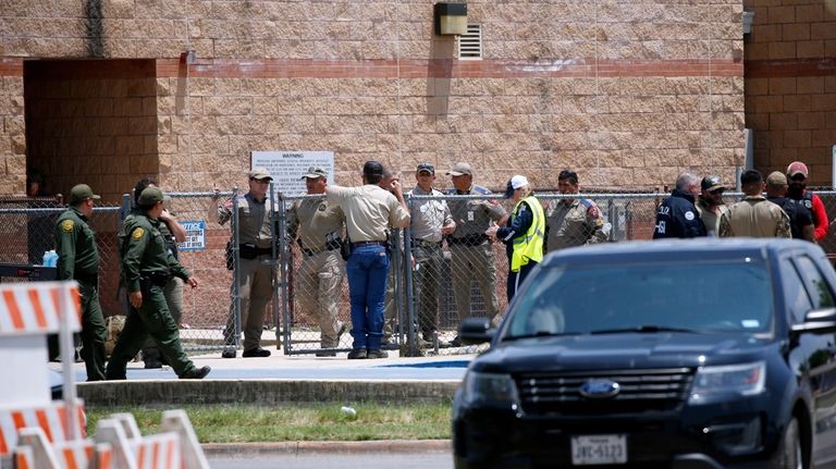 Law enforcement, and other first responders, gather outside Robb Elementary...