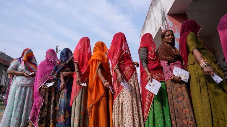 FILE- Women stand in a queue to cast their votes...