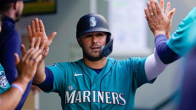 Seattle Mariners' Ty France is greeted in the dugout after...