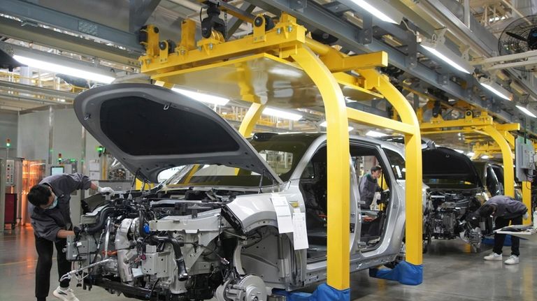 A worker assembles an SUV at a car plant of...