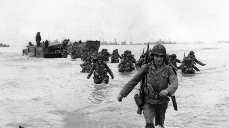U.S. infantrymen wade through the surf as they land at...