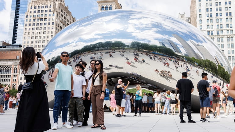 Visitors take photos of the "Cloud Gate" sculpture, also known...
