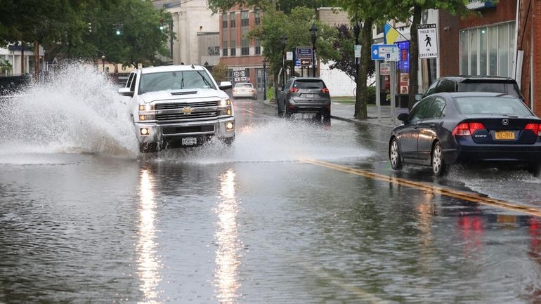 Vehicles navigate through flooding on Main Street, west of Griffing...