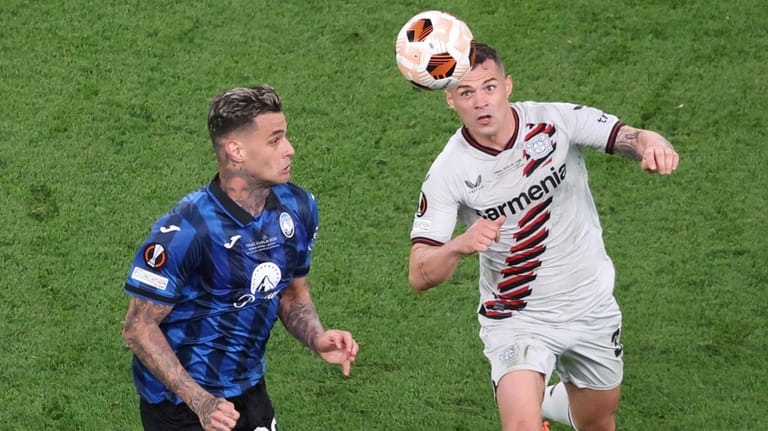 Atalanta's Gianluca Scamacca, left, and Leverkusen's Piero Hincapie go for...
