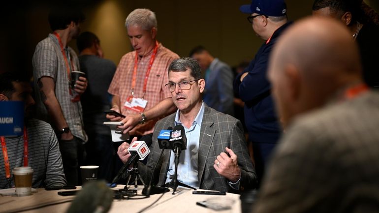 Los Angeles Chargers head coach Jim Harbaugh talks with reporters...