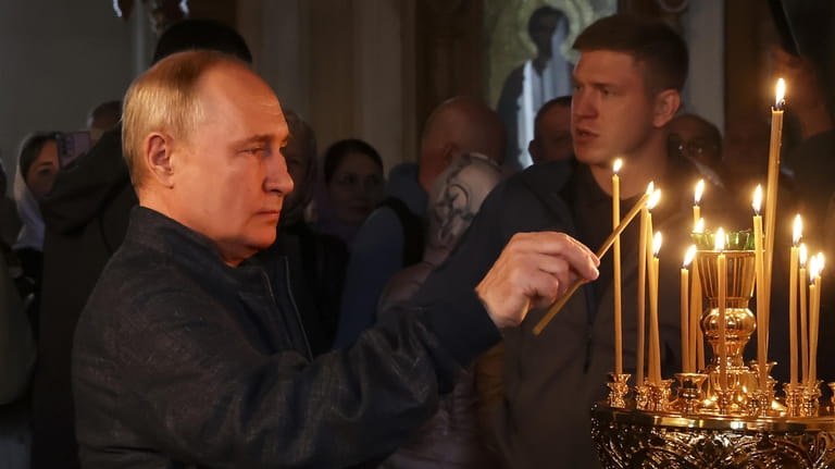 Russian President Vladimir Putin lights a candle as he visits...