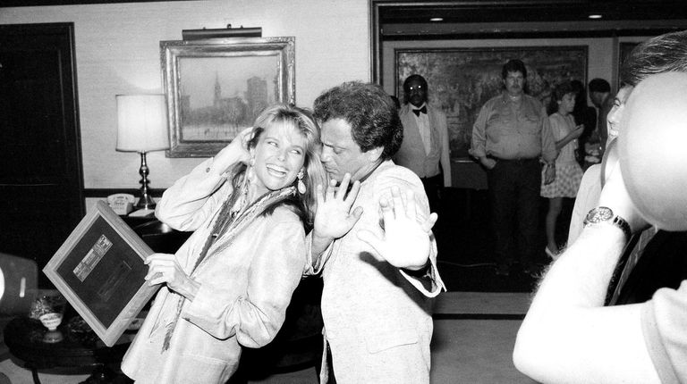 Billy Joel dances with then-girlfriend Christie Brinkley as she holds onto...