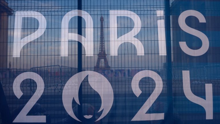 The Eiffel Tower is seen behind a Paris Olympics canvas,...