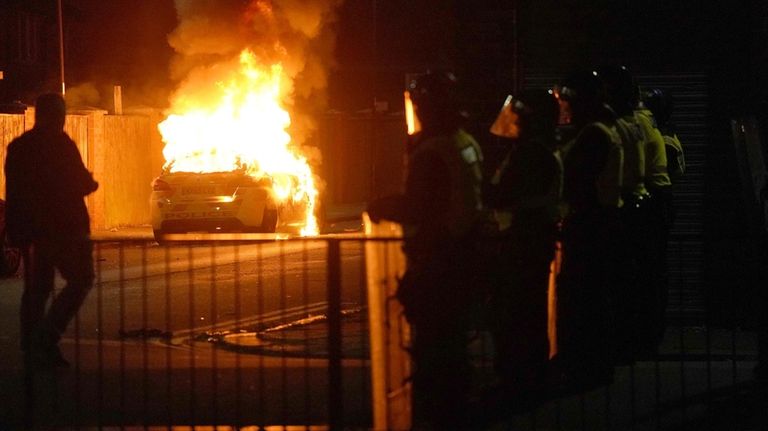 A police car burns as officers are deployed on the...