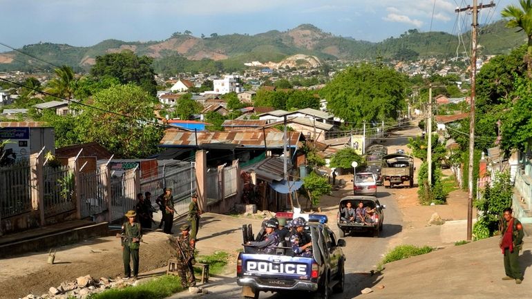 Army officers stand guard as police officers patrol in Lashio,...