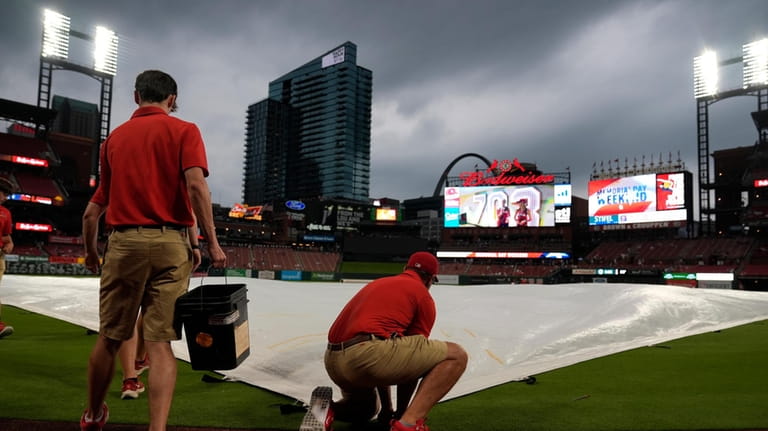 Members of the Busch Stadium grounds crew place a tarp...
