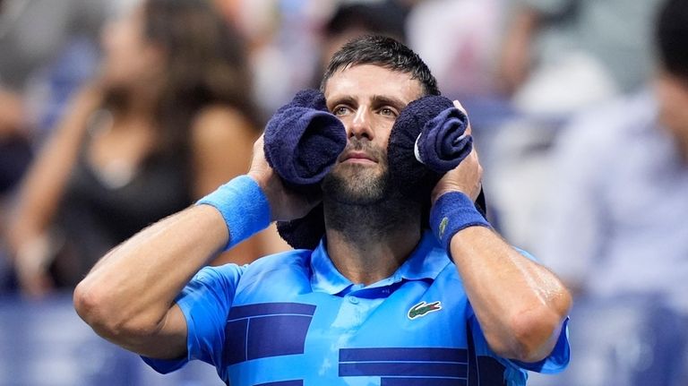 Novak Djokovic, of Serbia, puts a towel around his neck...